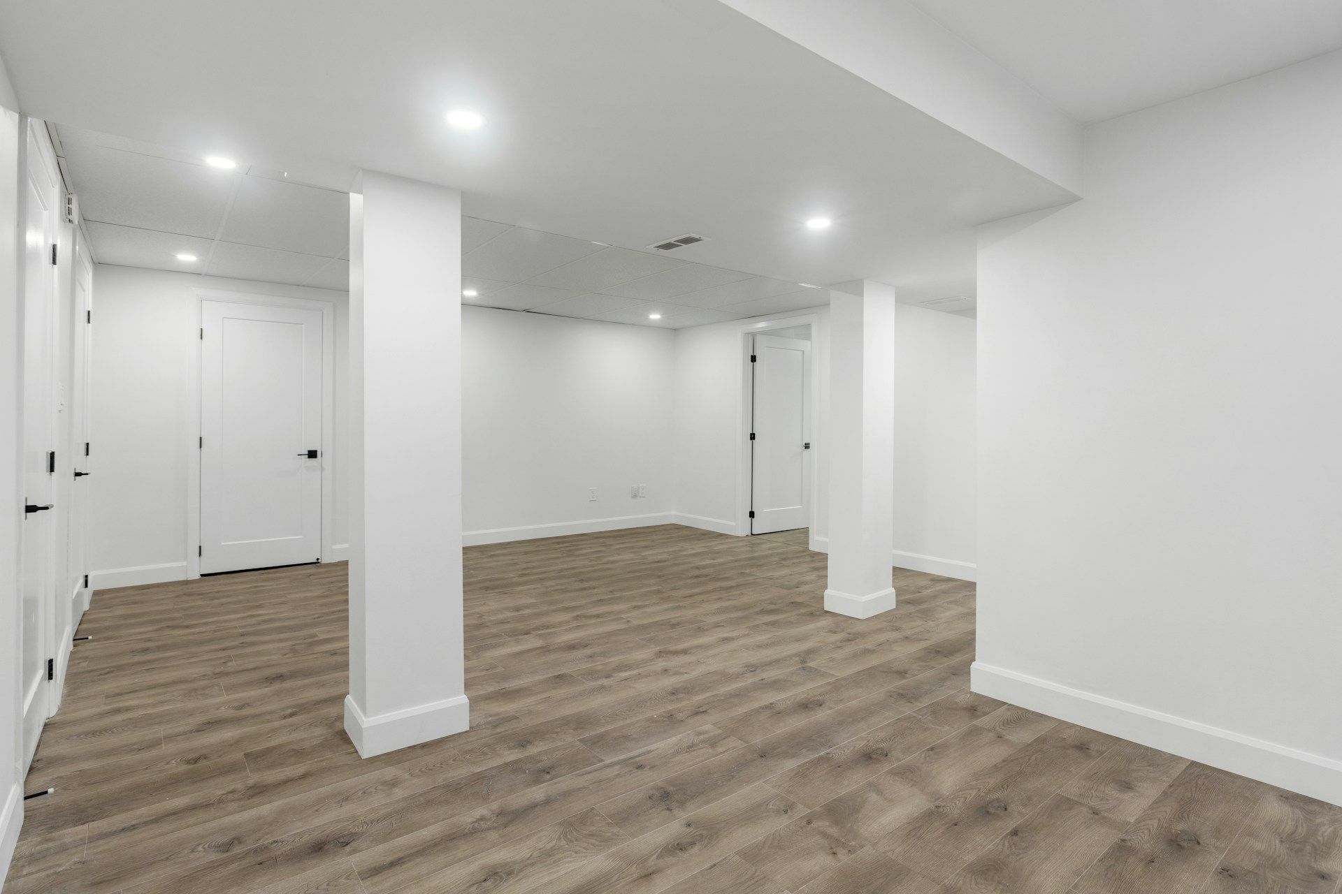 Clean finished basement with recessed lighting and LVP flooring
