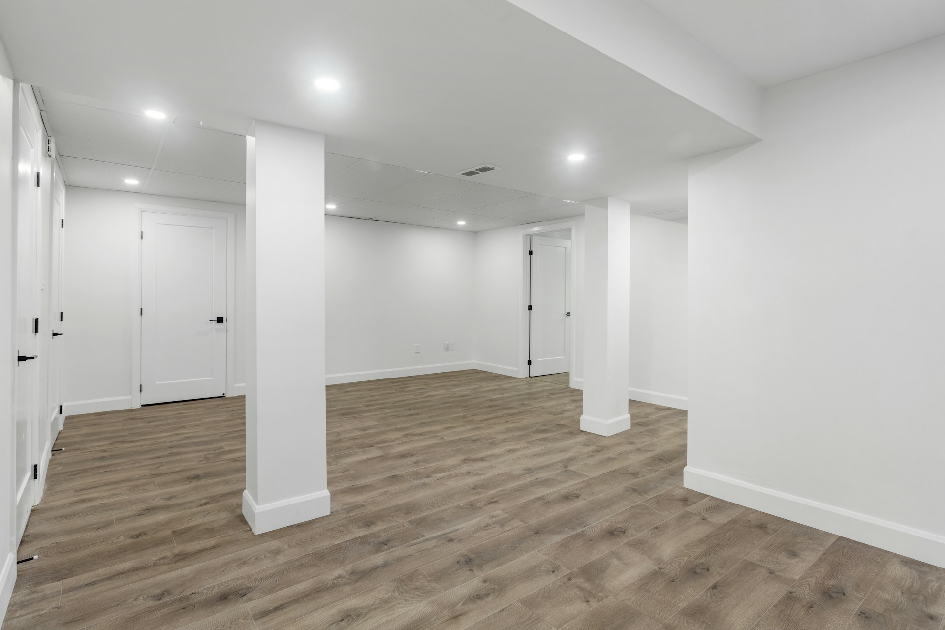 Clean finished basement with recessed lighting and LVP flooring